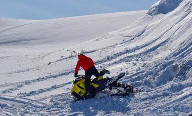 A man is riding snowmobile in mountains. Beautiful day in Swedish Lapland.