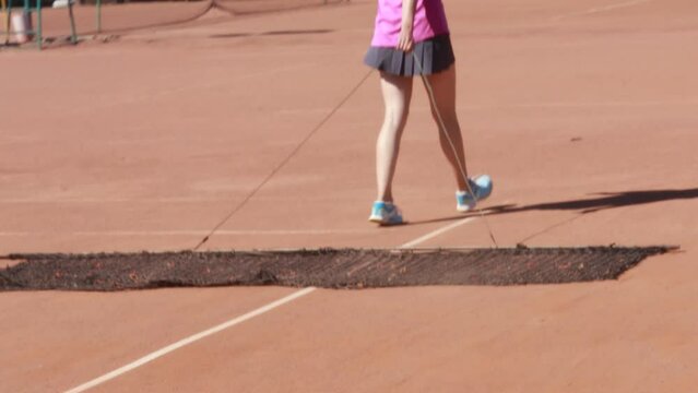 Caucasian woman cleaning court after playing tennis match on clay surface maintenance sweeping harvesting with web, wear skort, shoes. Female player ready to go home. 
