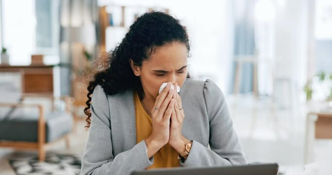 Covid, laptop and a business woman blowing her nose while suffering from allergies at work in the office. Flu, tissue and sneezing with a young female employee working online using a computer