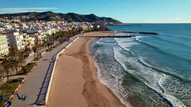 Aerial panoramic view of coastal village, Sant Bartomeu i Santa Tecla de Sitges during sunny day in Sitges, town near Barcelona in Catalonia, Spain. It is famous for its beaches. Film intro. 4K video
