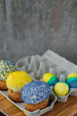 Easter cakes in the colors of the flag of Ukraine, yellow and blue in a cardboard stand with eggs, Easter eggs. place for text. selective focus