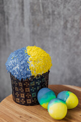 Easter cake is decorated with yellow-blue sprinkles on a gray background. place for text. patriotic paska in the color of the flag of Ukraine. Easter eggs