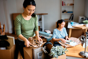 Asian woman packing her belongings while preparing to move out of her apartment.