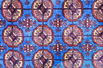 Close-up of colorful handmade silk carpet with pattern in red tones, traditional uzbekistan style.
