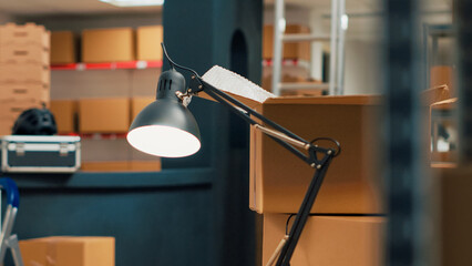 Storage room filled with cardboard boxes on shelves and racks, empty warehouse used to ship...
