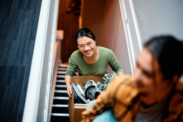 Happy Asian woman and her roommate moving into new apartment. - obrazy, fototapety, plakaty