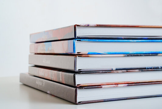 photobooks stacked on top of each other on a white table.