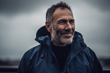 Fototapeta premium Portrait of a handsome middle-aged man with gray hair, wearing a blue jacket, standing in the rain.