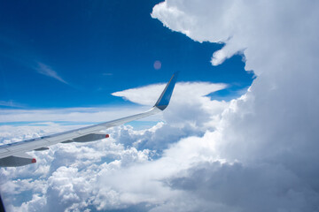 Vista del ala de un avión pequeño al lado de formaciones nubosas en un cielo azul intenso