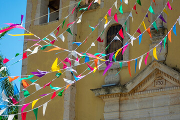 Vista parcial de fachada de iglesia donde se aprecian banderines de fiesta