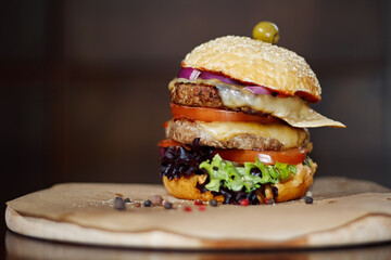A large and tasty burger with two patties on a board with seasonings