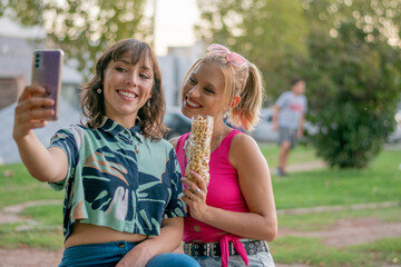 Two friends smiling and posing for a selfie in the park.