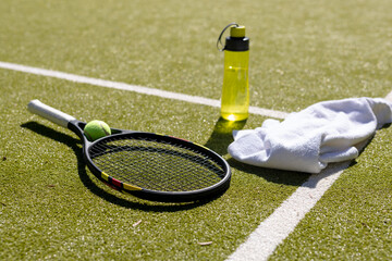 Close up of tennis ball, racket, towel and water bottle at tennis court