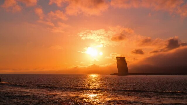 Time-lapse of Torre VTS de Lisboa - VTS Vessel Traffic System tower - Centre for Coordination and Control of Maritime Traffic and Safety of Lisbon on bank of Tagus river, Portugal on sunset. Zoom out