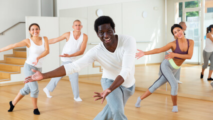 Fototapeta na wymiar Excited young man dancing with group of friends in dance studio
