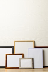 Vertical of six various empty frames with copy space on table against white wall