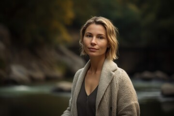 Portrait of a beautiful woman in a coat on the background of a mountain river