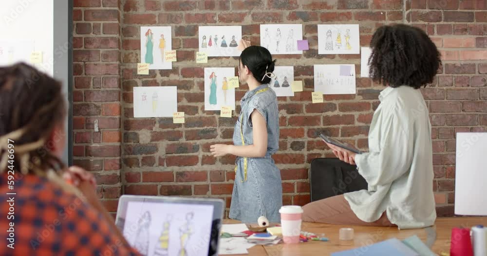 Poster busy diverse designers using tablet and discussing work in fashion design studio in slow motion