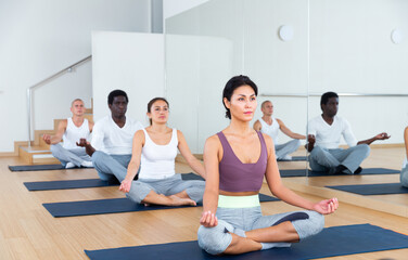 Obraz premium Man and woman making yoga meditation in lotus pose in fitness center