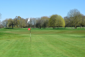 Putting green on a golf course on a sunny day with view of the fairway