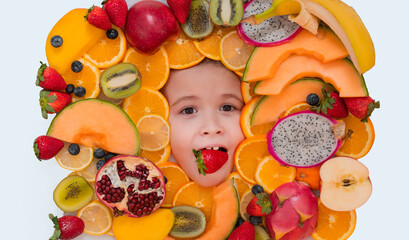 Fototapeta na wymiar Kid tasting fruits. Strawberry in child mouth. Healthy vitamins fruits. Kids face with mix of fresh frutis. Healthy nutrition food for kids.