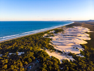 Aerial view of massive large sand dunes and Pacific ocean at sunset. Hat Head National Park, NSW, Australia