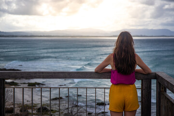 Beautiful long-haired girl stands admiring the magnificent rocky coastline and beaches in the...