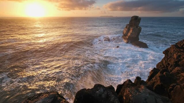 Ocean cliff and rock by the sea at sunset with crashing waves at cape Cabo Carvoeiro, Peniche, Portugal 