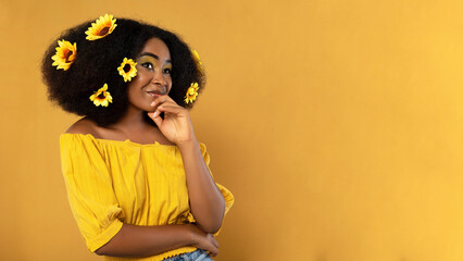 beautiful model posing on a yellow horizontal background, and is smiling.  curly girl in yellow hair holding her chin smiling in a yellow studio