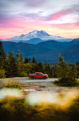 A pickup truck in front of volcanic mountain. Mount Rainier in the background in Washington State. A perfect spot for camping off the grid. - obrazy, fototapety, plakaty