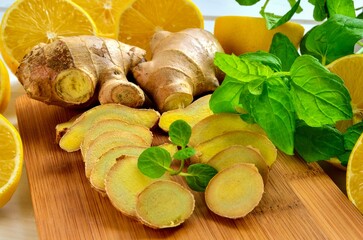 Lemons, ginger and mint leaves. Lemon halves, slices of ginger and mint leaves on a wooden board.