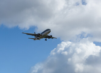 Fototapeta na wymiar The plane flies in the blue sky with clouds.