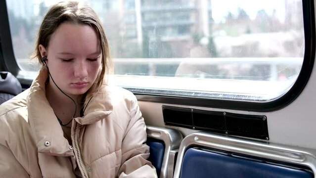 Vancouver Canada a girl is sitting near the window of the skytrain no one is visible near her only blue empty seats She 