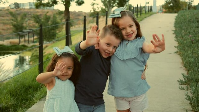 ni&ntilde;os hermanos amigos primos felices disfrutando de su amistad jugando riendo en el parque saludando al aire libre en un hermoso atardecer en un d&iacute;a soleado muy juguetones y felices