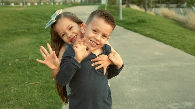 ni&ntilde;os hermanos amigos primos felices disfrutando de su amistad jugando riendo en el parque saludando al aire libre en un hermoso atardecer en un d&iacute;a soleado muy juguetones y felices