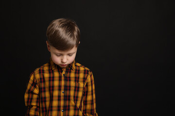 Upset boy on black background, space for text. Children's bullying
