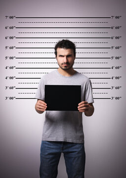 Criminal mugshot. Arrested man with blank card against height chart