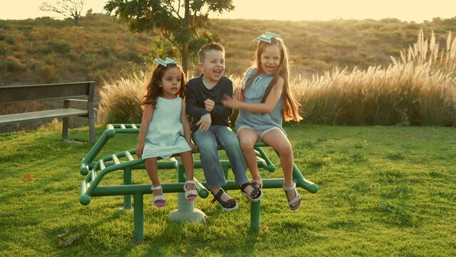 Ni&ntilde;os hermanos amigos primos tiernos y amorosos jugando y disfrutando riendo divertidos y sonrientes en un hermoso d&iacute;a soleado al atardecer al aire libre en el parque