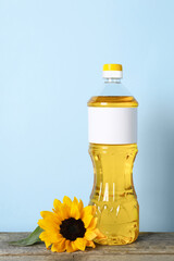 Bottle of cooking oil and sunflower on wooden table