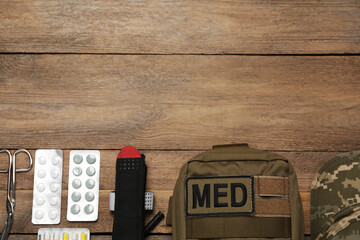 Flat lay composition with military first aid kit on wooden table. Space for text