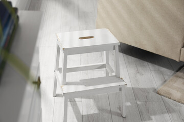 White compact ladder on wooden floor indoors