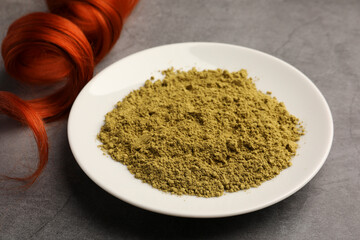 Henna powder and red strand on light grey table. Natural hair coloring