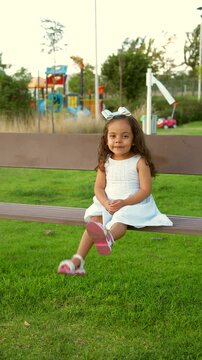 Ni&ntilde;a peque&ntilde;a chiquita bebe hermosa latina sonriente tierna amorosa jugando disfrutando y saludando a la c&aacute;mara sentada en una banca divertida en un hermoso d&iacute;a soleado al atardecer en el parque