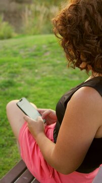 Mujer persona muchacha chica chava escribiendo en el celular haciendo anotaciones en su telefono texteando en el atardecer en el parque al aire libre descansando relajandose