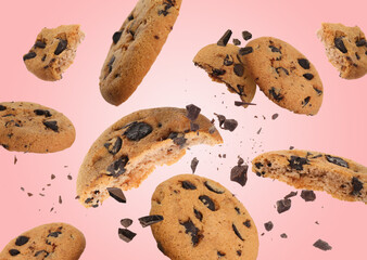 Tasty chocolate chip cookies falling on pink background