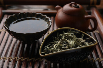 Aromatic Baihao Yinzhen tea and teapot on wooden tray, closeup. Traditional ceremony