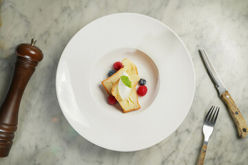 Baba Au Rhum with raspberry, blueberry, cream and bread served in dish isolated on marble background top view on hong kong food