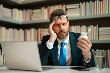 Business man in suit with headache. Tired businessman is working overtime and has headache. Medicine pill from headache migraine. Migraine from overwork, deadline.