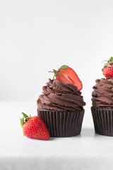 Chocolate cupcake with dark chocolate buttercream and strawberries, double chocolate cupcakes with american buttercream, tall swirl frosting on a cupcake with a strawberry