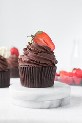Chocolate cupcake with dark chocolate buttercream and strawberries, double chocolate cupcakes with american buttercream, tall swirl frosting on a cupcake with a strawberry